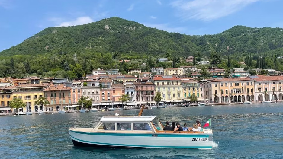 Tourist motorboat cruising along the scenic waterfront of Salò on Lake Garda, Italy.