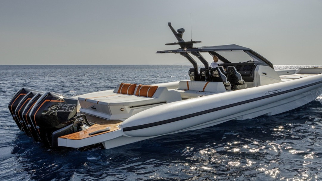 Luxury motorboat viewed from the back, man steering the boat with comfortable rear seating and sun loungers visible