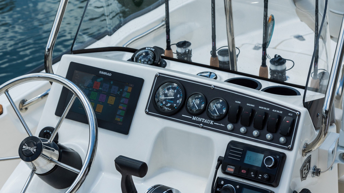 Modern boat steering wheel and control panel of a rental boat, featuring a high-tech display and numerous buttons