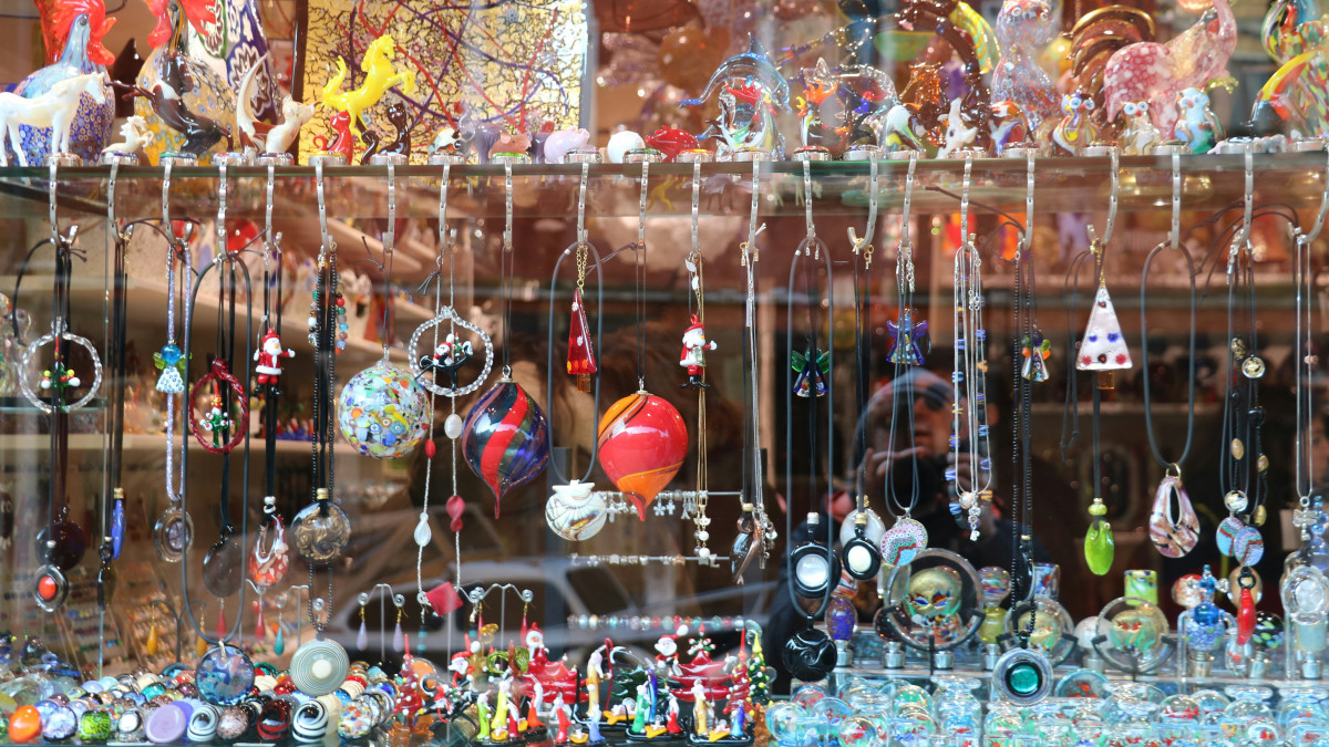 Handmade Murano glass jewelry and colorful ornaments displayed in a traditional Venetian glass shop window