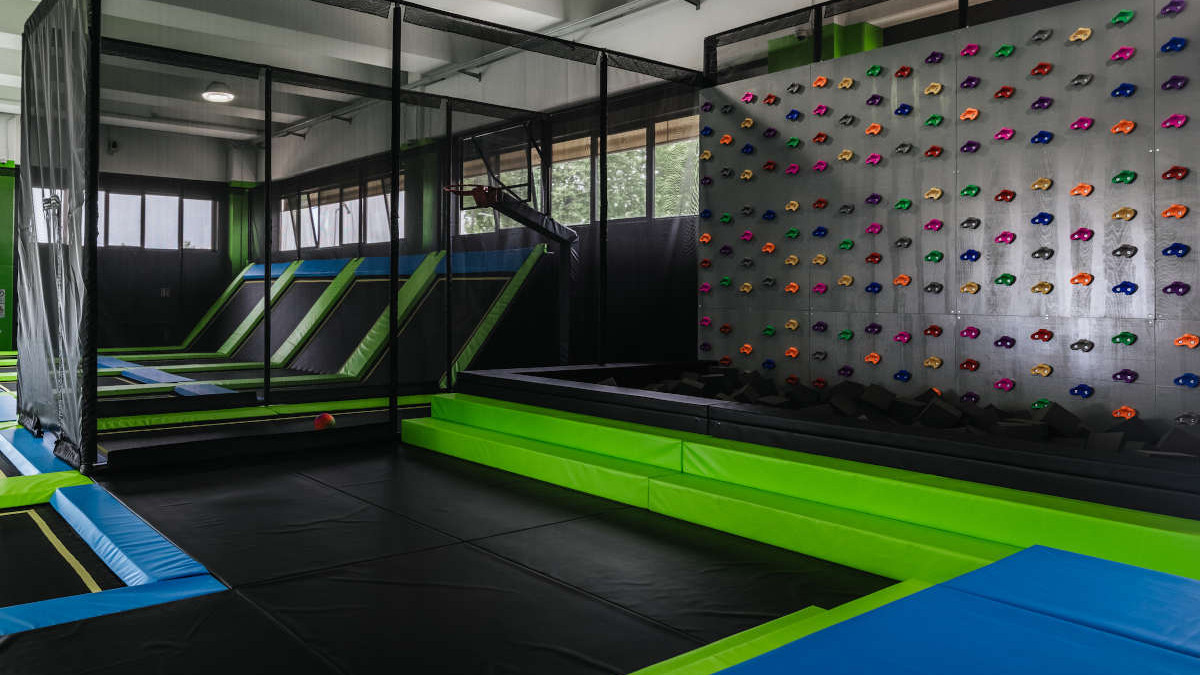 Just Jump Jesolo indoor sports center: modern gym equipment with trampolines, climbing wall, and safety foam pit for kids and adults.
