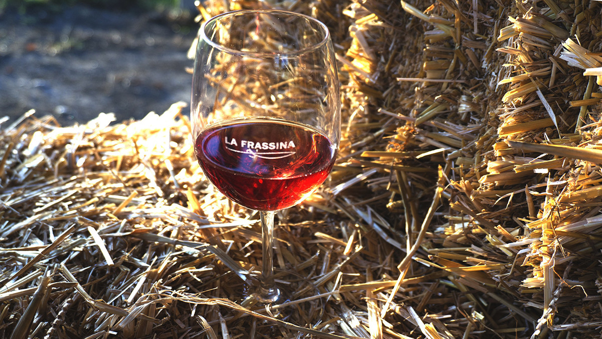 Wine tasting at Cantina La Frassina in Caorle; high-quality rosé wine in a branded glass at a rural vineyard event