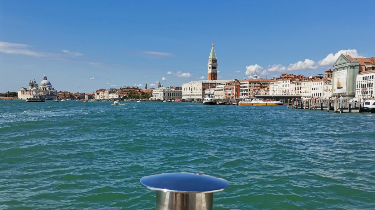 View of Venice skyline and St. Mark’s Campanile from a boat on the Venetian Lagoon, featuring the Doge's Palace and Santa Maria della Salute.