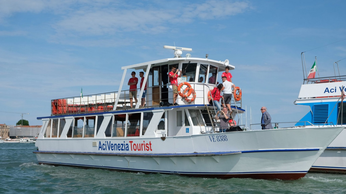 Aci Venezia Tourist sightseeing boat with passengers on the open-top deck navigating the Venice lagoon.