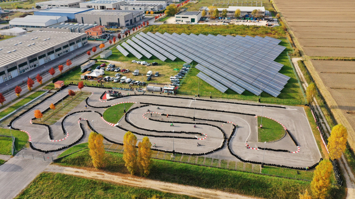 Aerial view of Go-Kart Torracing outdoor track in Italy featuring a technical asphalt circuit, solar panel farm, and paddock area.