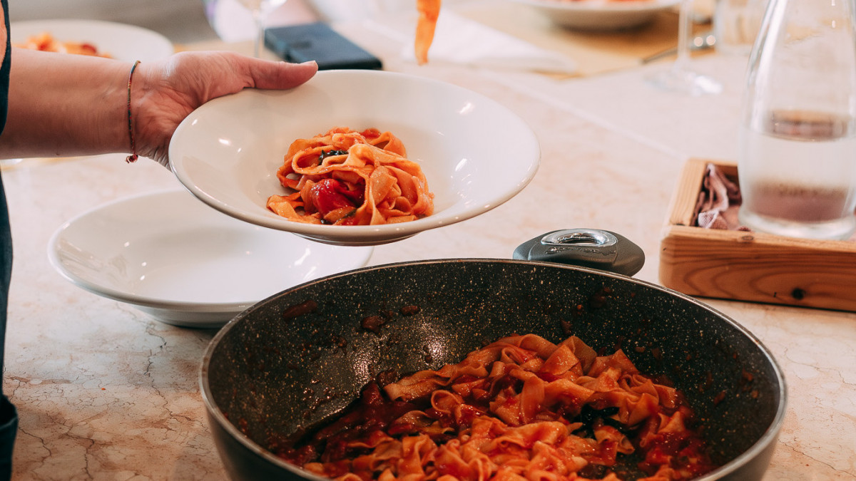 Pasta with fresh tomato sauce, sautéed in a pan and beautifully served on plates.