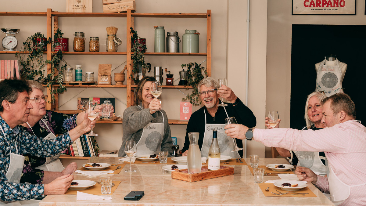Participants gathered around the table, laughing and cheering as they celebrate their creations during the cooking class.