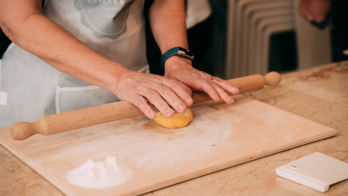 A participant carefully kneading fresh pasta dough during the cooking class.