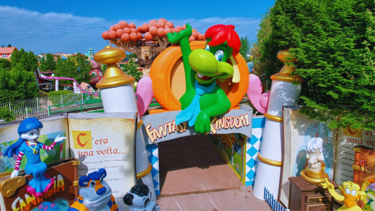 The colorful entrance to Fantasy Kingdom at Gardaland Park, Italy, featuring the Prezzemolo mascot statue and giant storybooks
