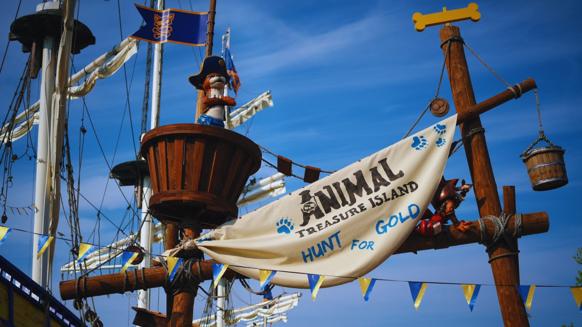 Pirate ship mast and "Animal Treasure Island - Hunt for Gold" banner at Gardaland Park, Italy, featuring a cat pirate statue in the crow's nest.