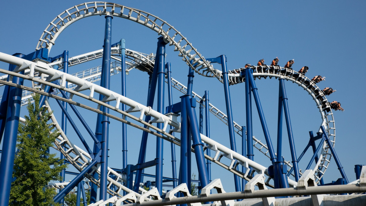Full view of the Blue Tornado inverted roller coaster tracks and riders against a clear blue sky at Gardaland Park, Italy.