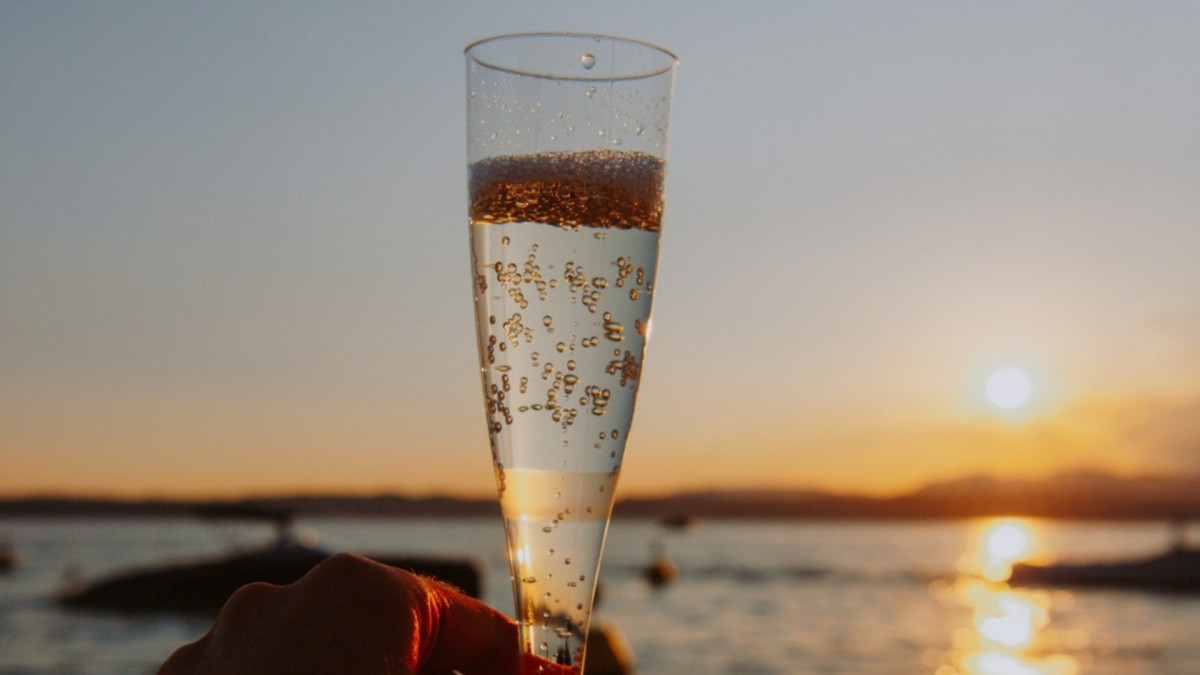 A glass of sparkling Prosecco wine held during a sunset boat tour by Bertoldi Boats on Lake Garda, Italy.