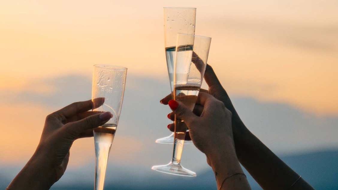 Close-up of friends making a toast with sparkling wine glasses during an exclusive sunset boat tour by Bertoldi Boats on Lake Garda