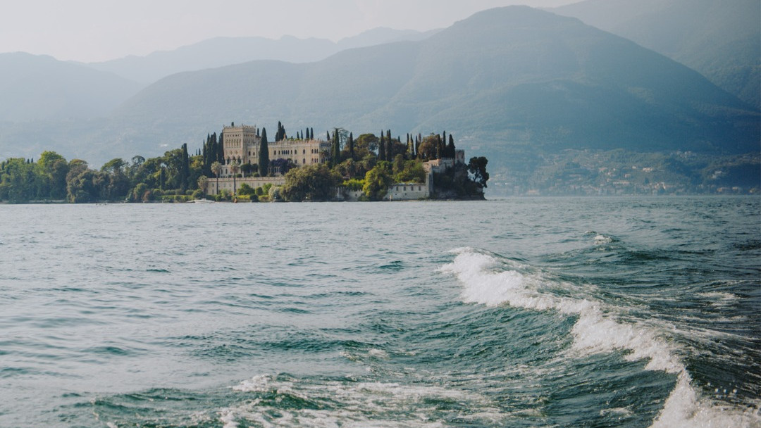 Panoramic view of Isola del Garda with its Venetian neo-Gothic villa seen from the water during a Bertoldi Boats boat tour on Lake Garda, Italy.