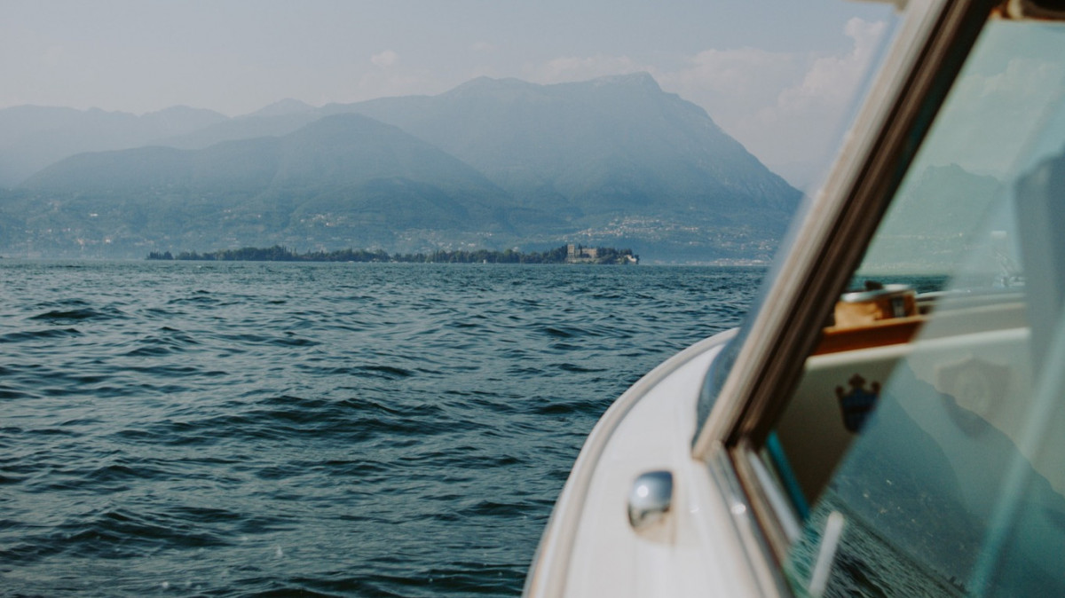 View from a motorboat deck cruising towards Isola del Garda on Lake Garda, Italy.