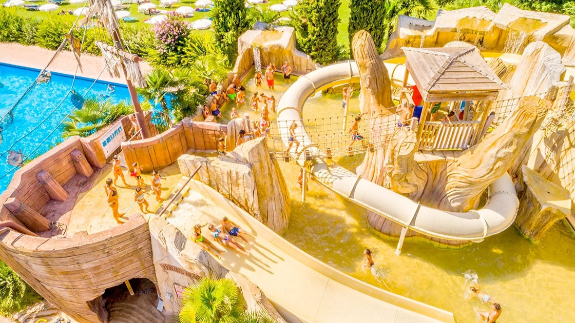 Aerial view of a pirate-themed water park attraction with artificial rock formations, slides, and a bridge at Cavour Waterpark