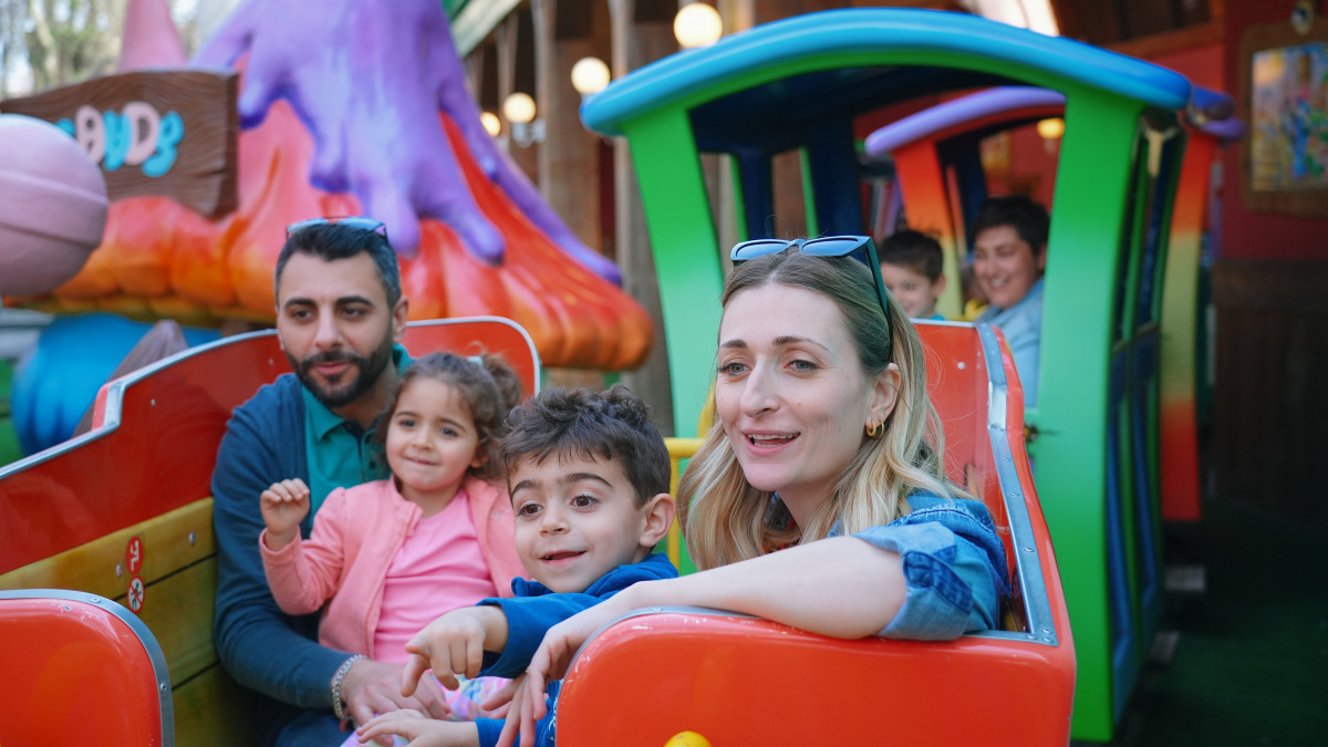 family enjoys a ride on the colorful Ortobruco Tour roller coaster at Gardaland, a popular Italian theme park, on a sunny day