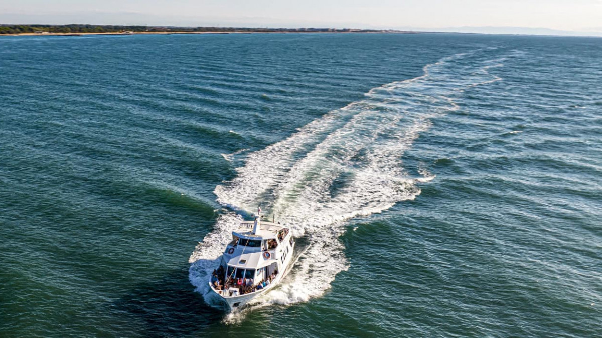Aerial view of a sightseeing tour boat cruising the Adriatic Sea near Caorle, Italy.