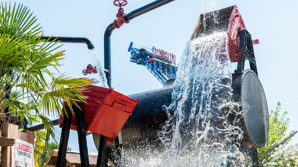 Massive water splash at the Twin Splash attraction in Caneva Acquapark, featuring giant tipping buckets and industrial-themed water play for families.