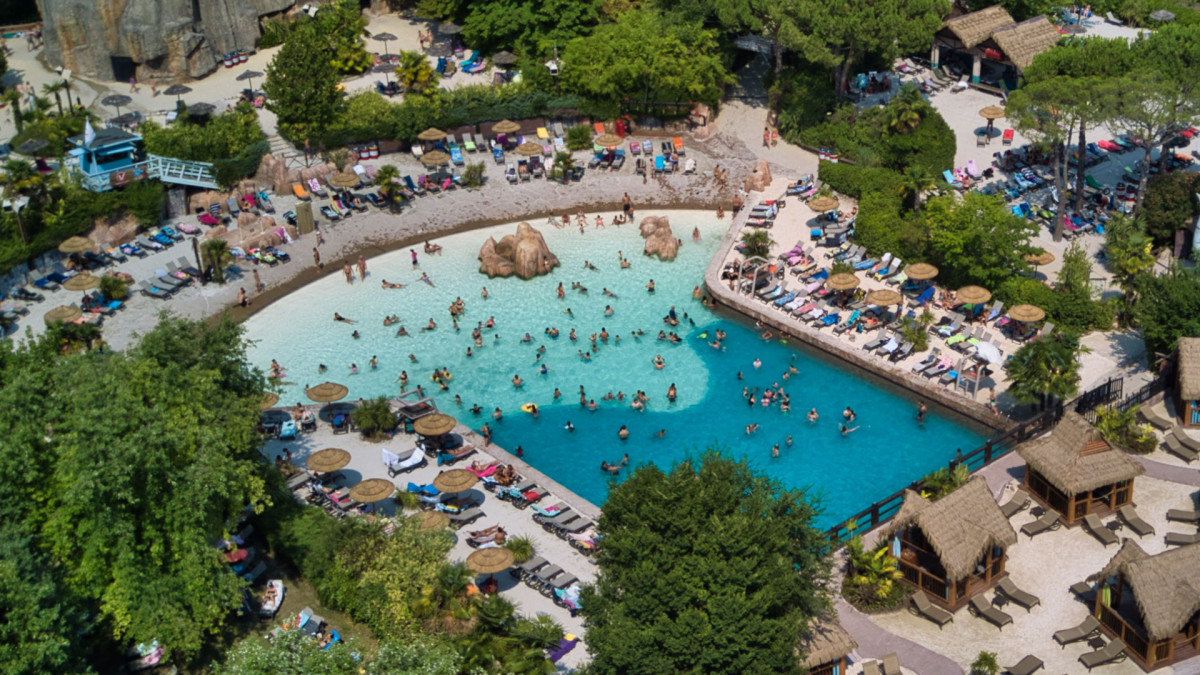 High-angle view of the white sand beach and tropical pool area at Caneva Aquapark, Lake Garda.