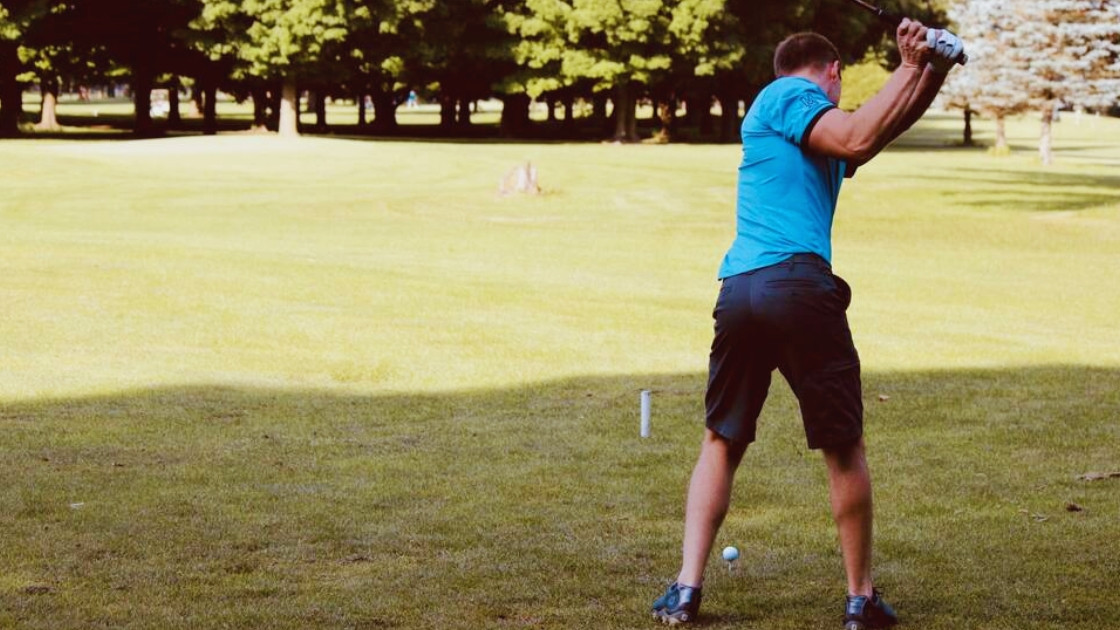 Golfer practicing his backswing on a sunny golf course during a summer training session.