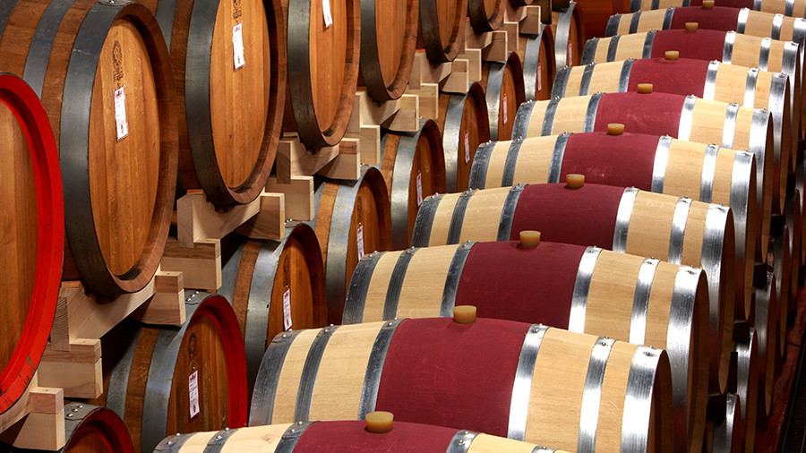 Rows of traditional oak barrels and large wine casks aging premium red wine in the historic cellar of Castello di Roncade