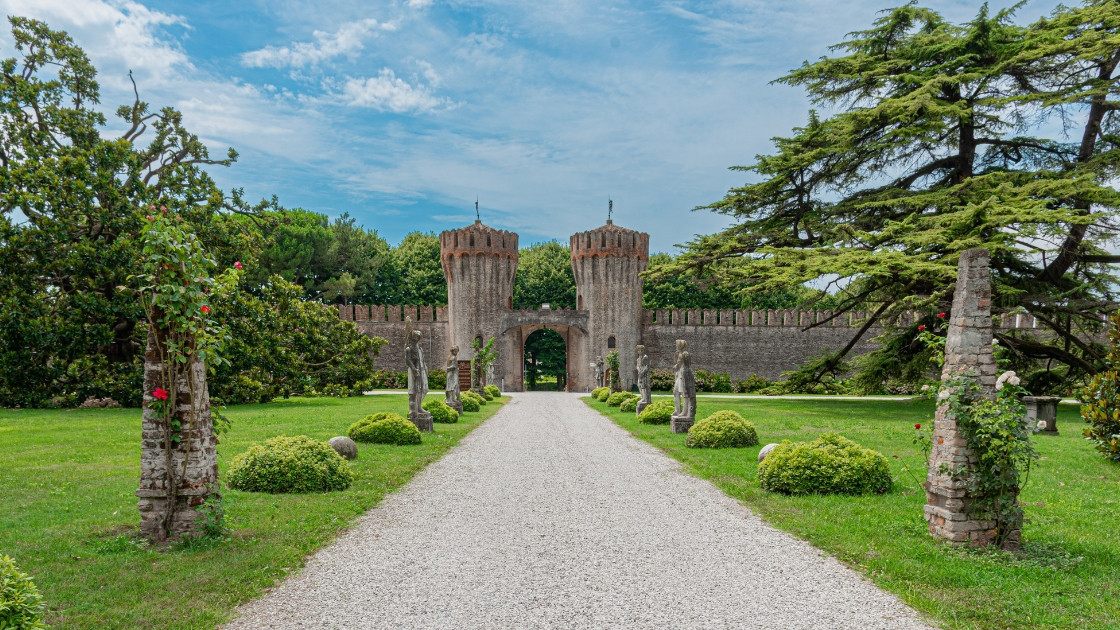 Long pebble driveway leading to the medieval twin towers and defensive walls of Castello di Roncade in Treviso, Italy, surrounded by historic gardens