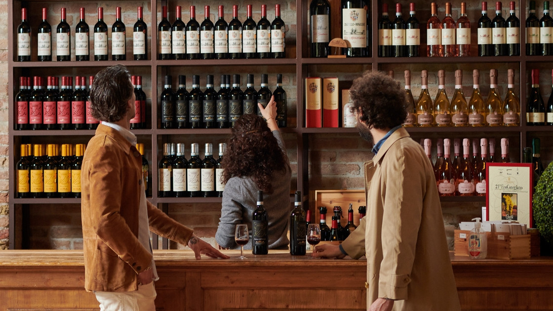Professional wine cellar display with rows of red and white wine bottles on wooden shelves at a historic Italian winery