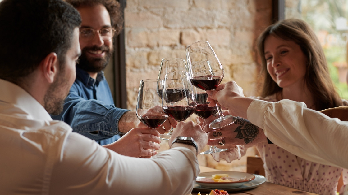 Friends toasting with glasses of red wine during a tasting at Castello di Roncade, featuring local Veneto cold cuts and cheeses