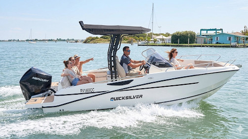 A white Quicksilver Activ open motorboat with a black T-top and Mercury outboard engine cruising on a sunny bay with four people on board.