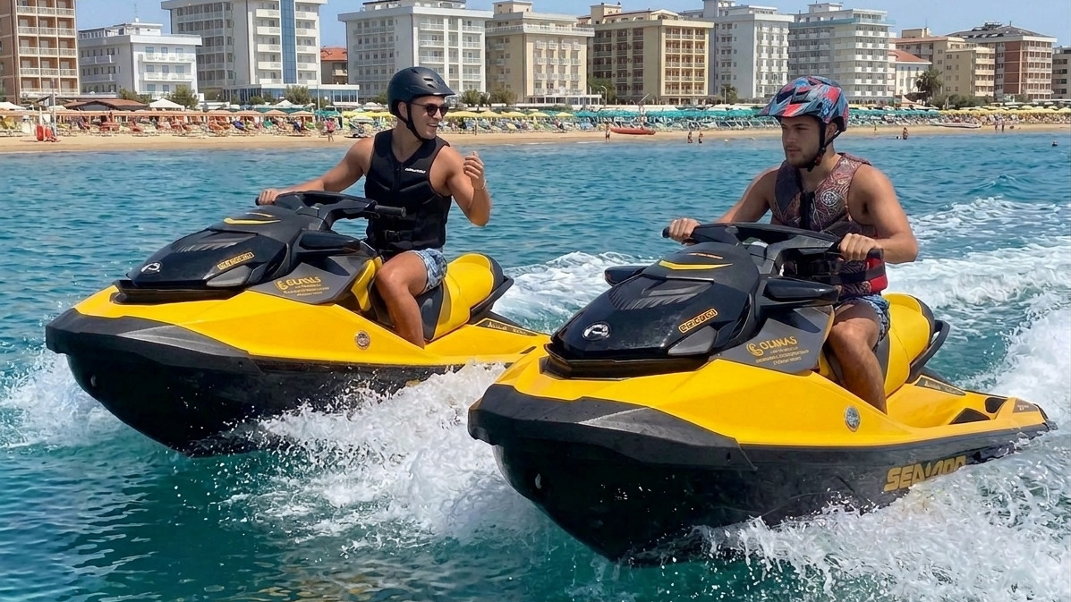 Two men riding yellow Sea-Doo jet skis side-by-side with water spray, on the sea near a resort beach in Italy.