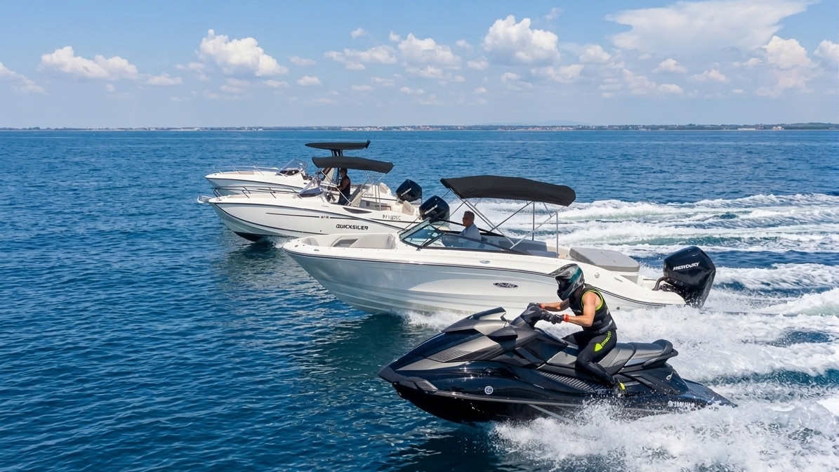 A group of white Quicksilver and Sea Ray motorboats cruising alongside a black Yamaha jet ski on blue open water under a sunny sky.